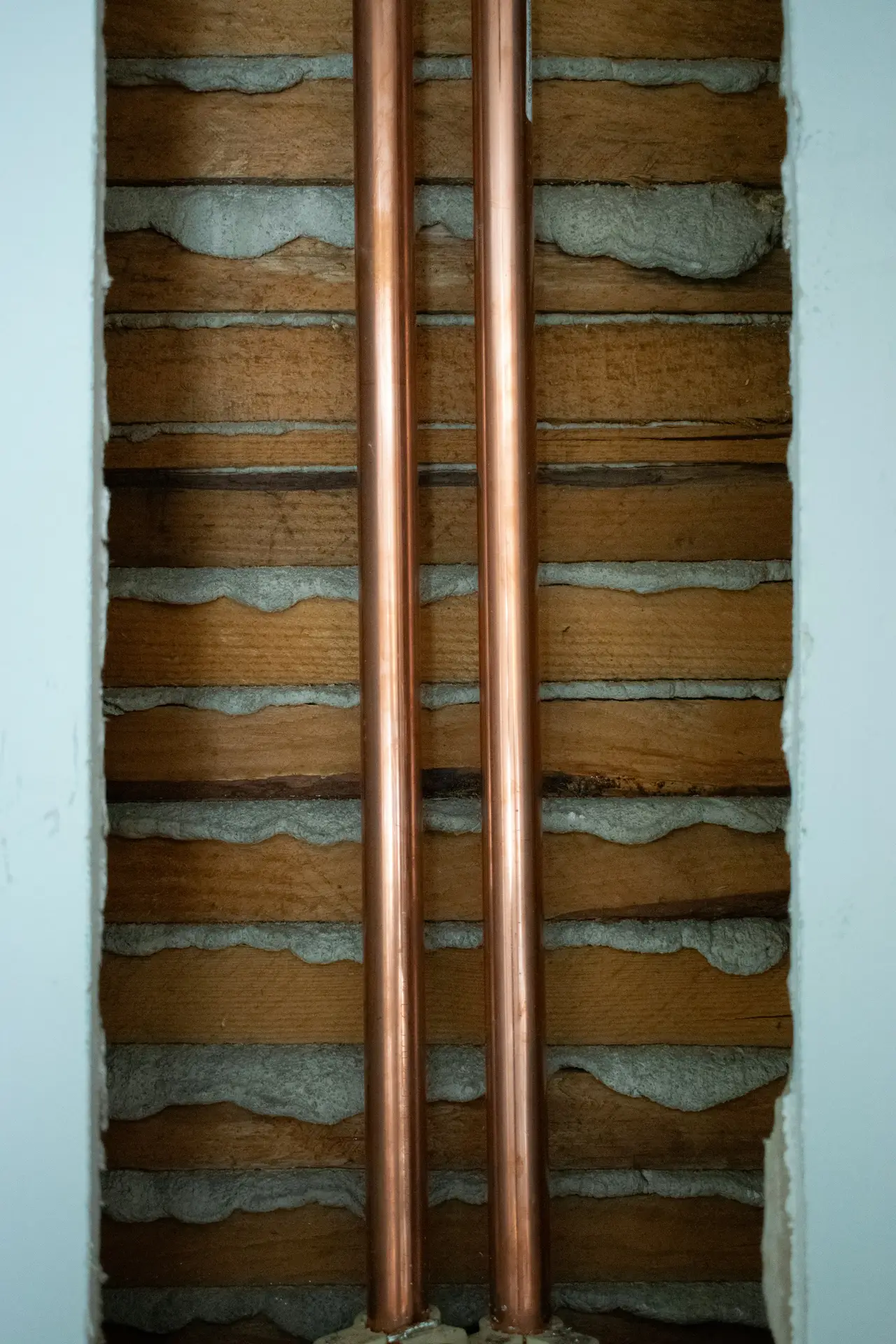 Copper pipes running through an opened lath and plaster wall