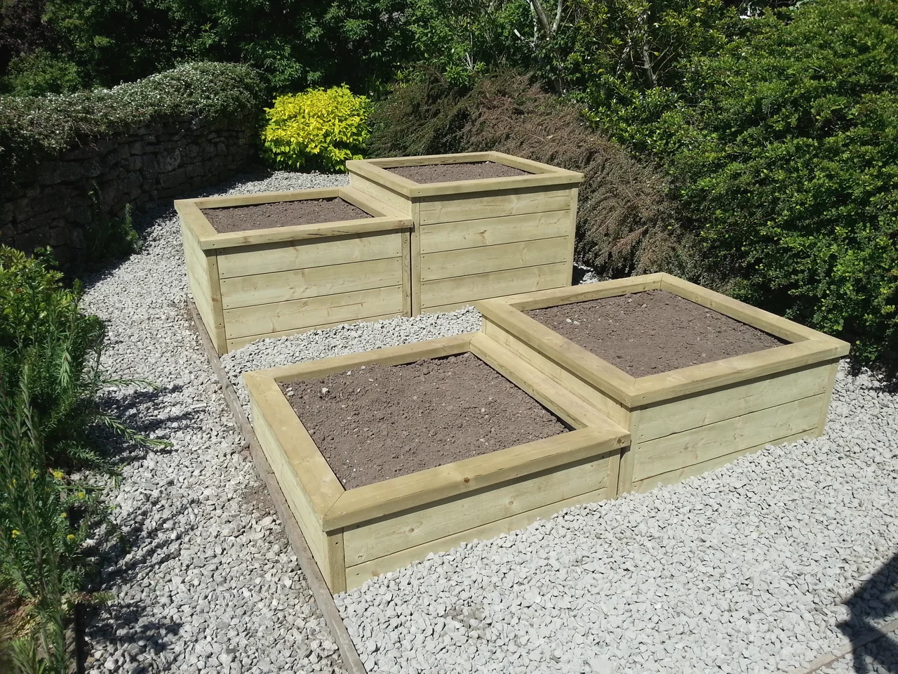 Four square timber raised planting beds stepped across a gravelled area