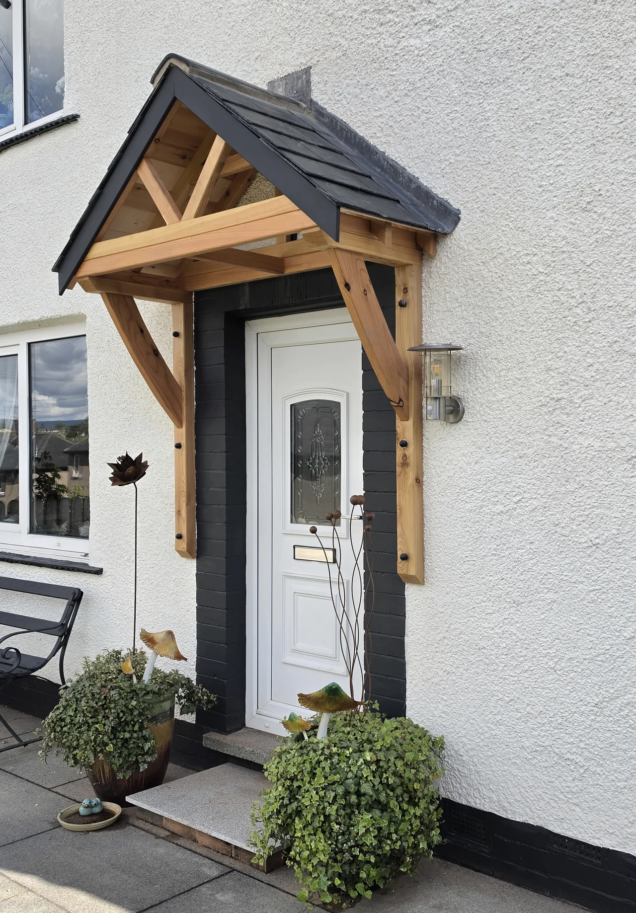 A pitched timber porch canopy with curved brackets and a slate roof above a white front door