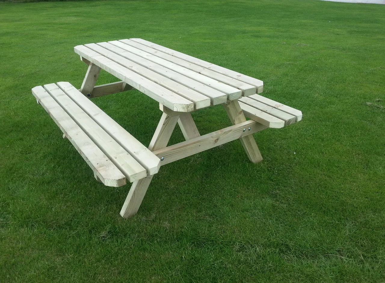 A sturdy timber picnic table with attached bench seats standing on grass